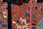 Wat Xieng Thong temple in Luang Prabang, Laos.  La Chapelle Rouge , the Red Chapel. The exterior walls are decorated with colourful mosaics on a pink background with scenes of people daily activities. South wall. 